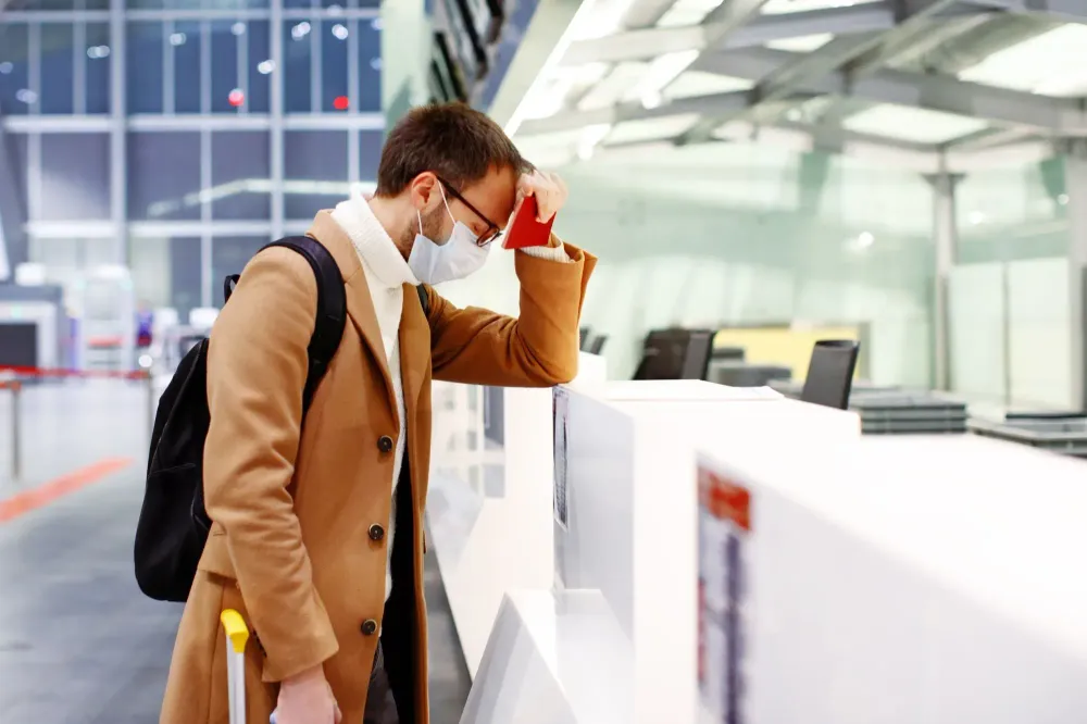 Man resting head in hands at airport guest check in desk